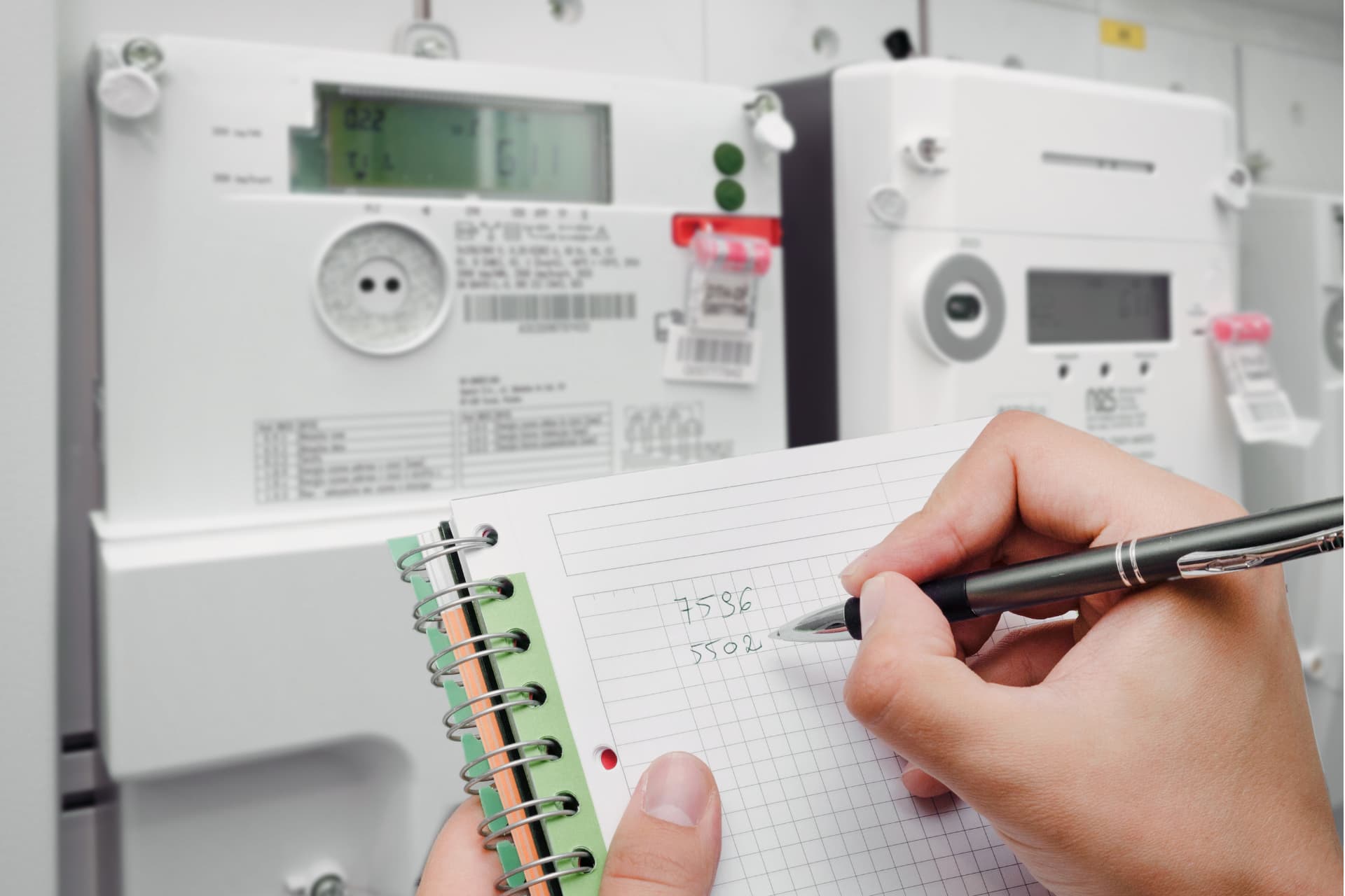 Person holding a notebook taking notes from energy meters
